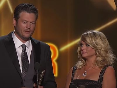 Blake Shelton and Miranda Lambert are on stage holding an award as Blake is speaking.
